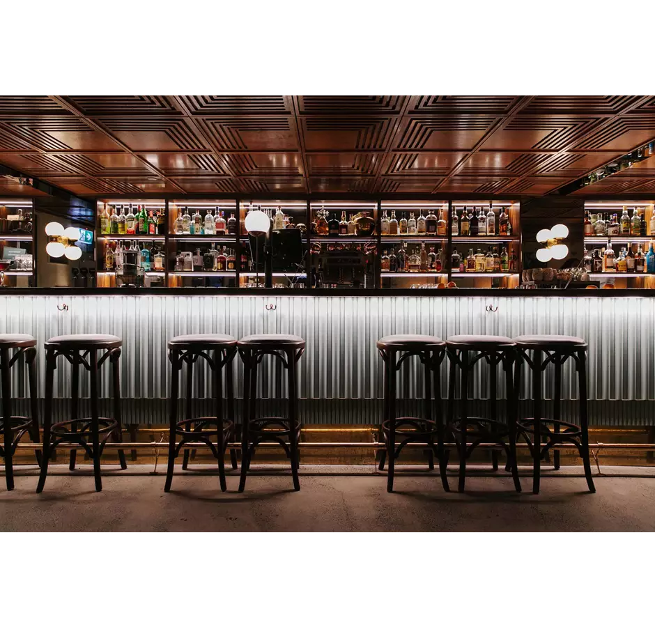 Austin Club bar with high bar stools and bottles in the background.
