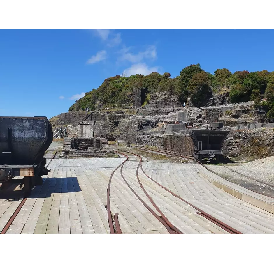 View of Denniston Coal mine with unused tracks and coal buckets. Hillside in the background.