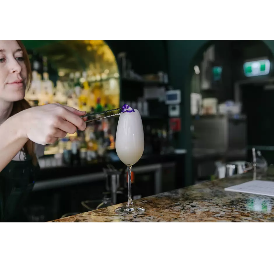 Woman Putting A Petal On Top Of A Cocktail At Gin Gin