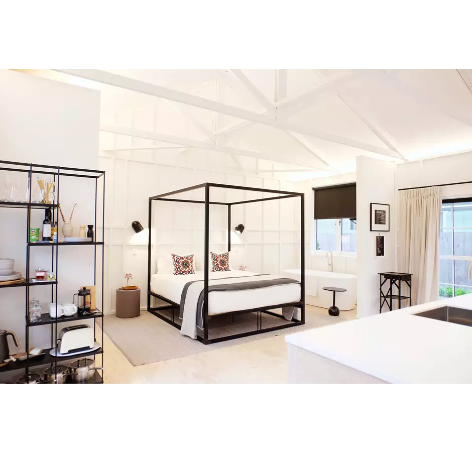 The Tack Rooms looking at queen bed with canopy and cushions.
