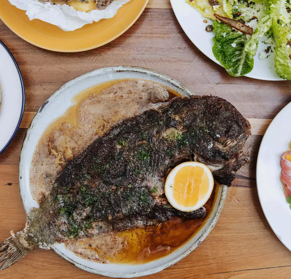 Whole fish served on a plate with a lemon at Gatherings.