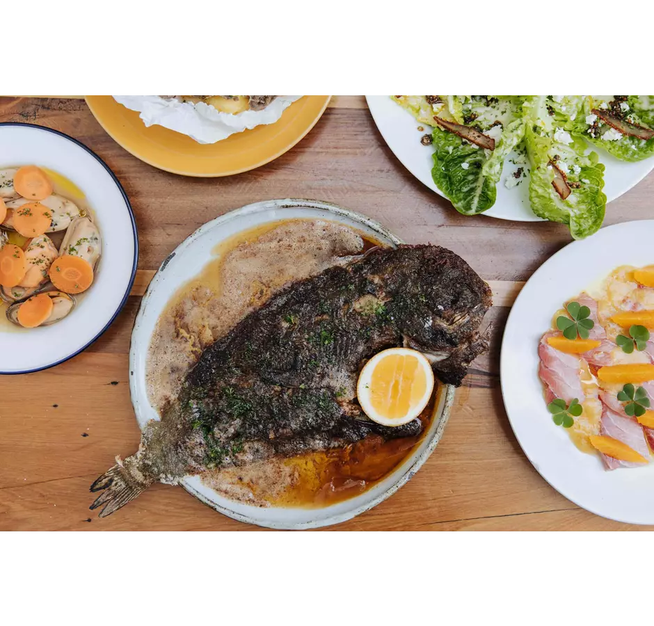 Whole fish served on a plate with a lemon at Gatherings.